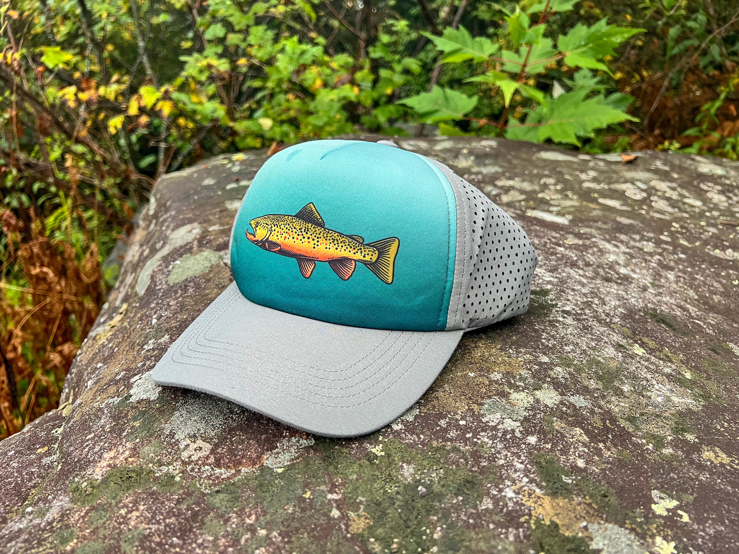 McClumsy Brown Trout Hat Outside on a rock with the front