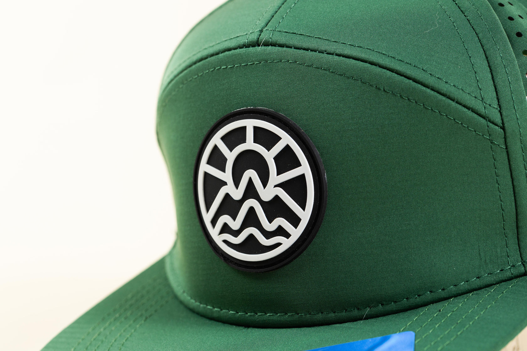 Black and White McClumsy Logo on the front of their Green 7 Panel Laser Cut Back Trucker Hat. 