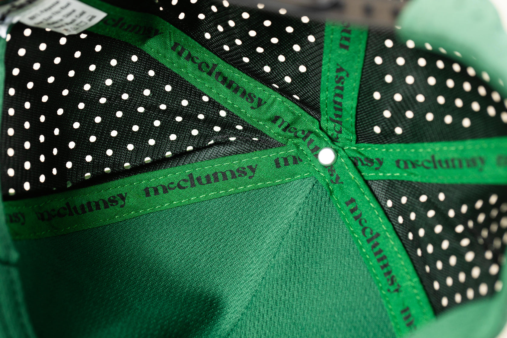 Inside view of the 7-Panel Green McClumsy Trucker Hat featuring sublimated seam tape and a wicking forehead liner. 
